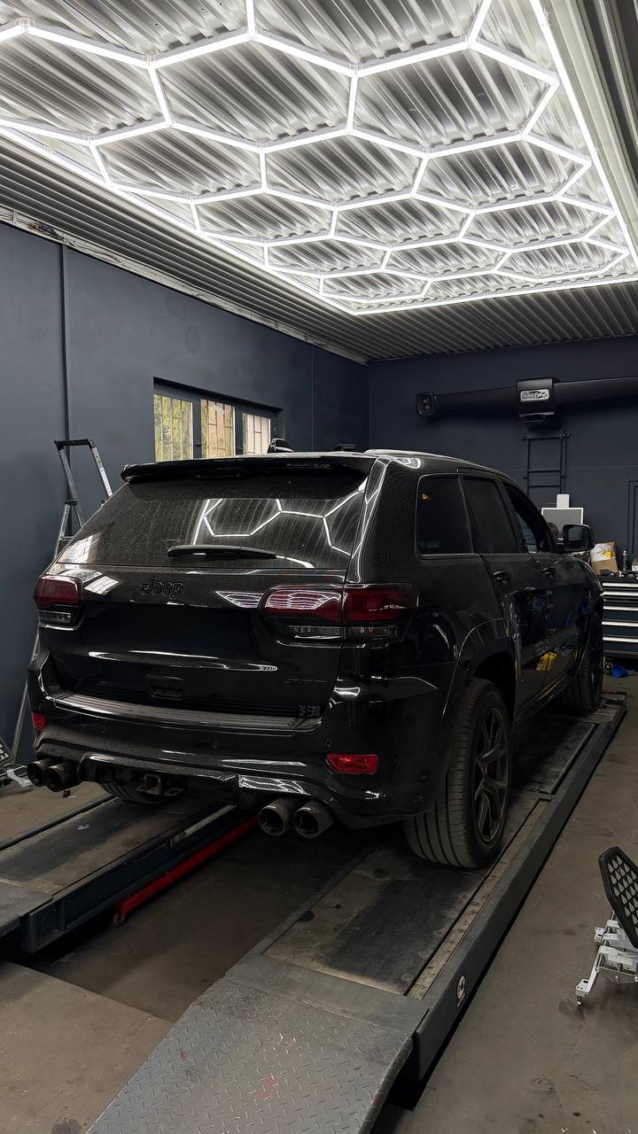 Black SUV on lift in garage with neon lighting