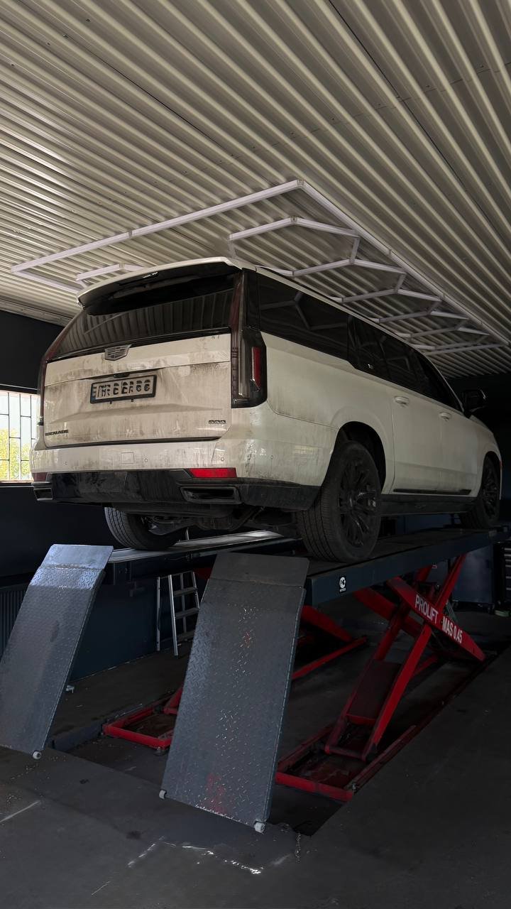 White car on red lift in garage with metal roof