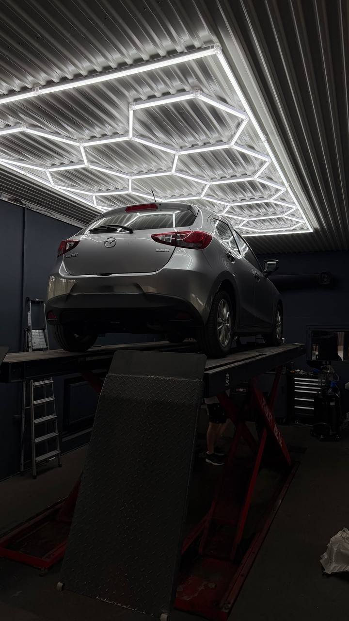 Gray Mazda on lift with neon lighting